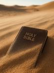 A Bible lying in the desert sand, partially obscured