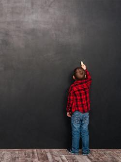 boy in flannel shirt drawing on a chalk board