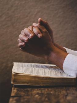 Praying hands over a bible