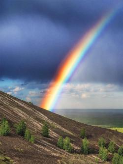 Rainbow on a hillside with storm clouds