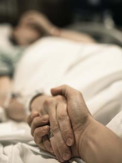 Dying person holding hands with a loved one