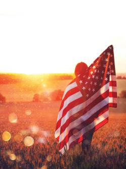 Woman at sunset holding up us flag