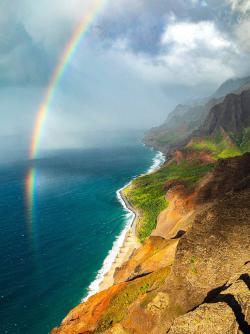 Rainbow over green rocky ocean shore