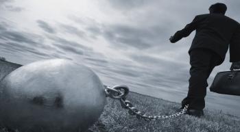 man holding breifcase with a chain around his ankle attached to a heavy ball