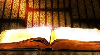 a bible with prison bars silhouetted in the background