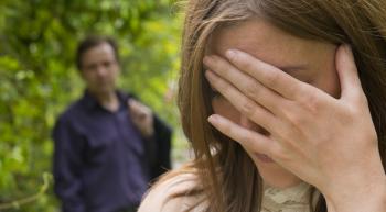 Stressed out woman with hand over her face and a concerned man looking on