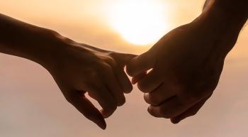 husband and wife's hands with fingers intertwined at sunset