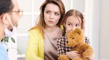 concerned mother with child on lap listening to a doctor talking