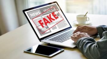 laptop with red "FAKE" across news website on screen