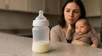 A pensive mother with her baby looks at a near-empty bottle of baby formula