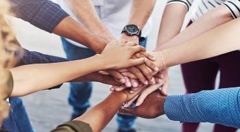 many hands on top of one another in center of circle