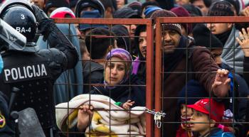 large crowd of migrants attempting to enter Slovenia at a padlocked gate