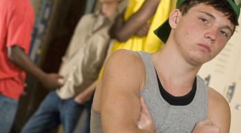 young man trying to look tough next to school lockers