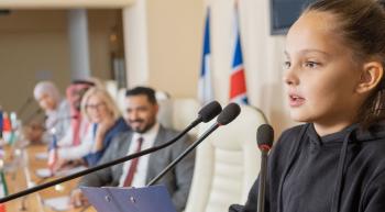 young girl at a podium speaking in front of adults