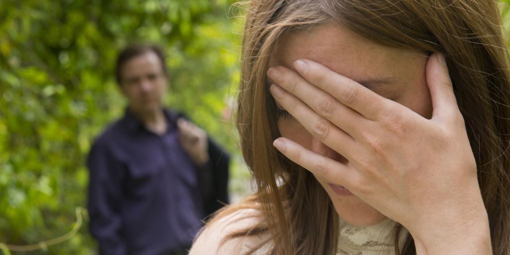 Stressed out woman with hand over her face and a concerned man looking on