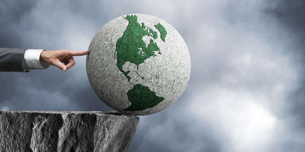 finger pushing a globe off the edge of a cliff