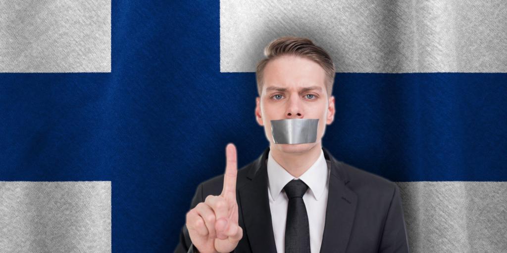 man with tape over his mouth in front of Finnish flag
