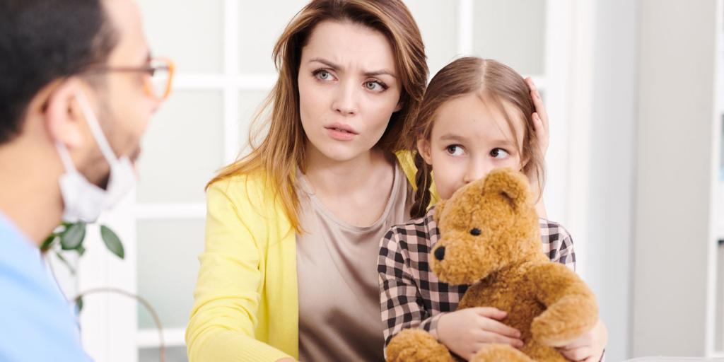 concerned mother with child on lap listening to a doctor talking