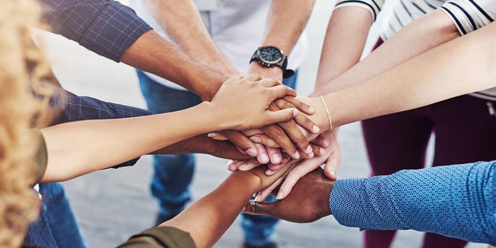 many hands on top of one another in center of circle