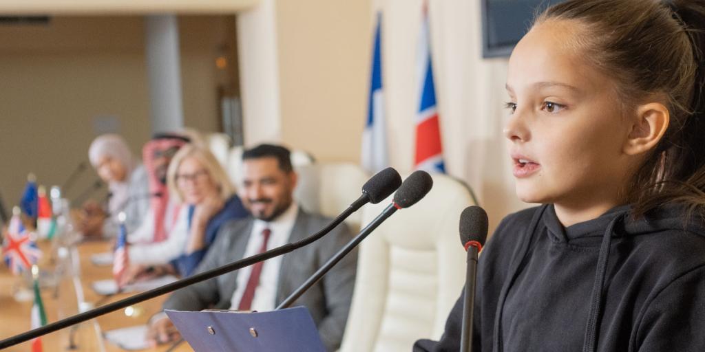 young girl at a podium speaking in front of adults