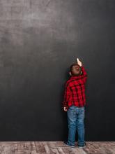 boy in flannel shirt drawing on a chalk board