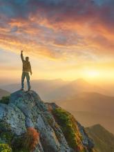 Man with arm upraised standing on mountain