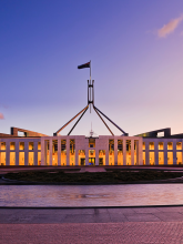 The main entrance of the Australian Parliament House in Canberra, under the glow of a beautiful sunset