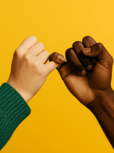 Two hands locked in a pinky promise set against a yellow background