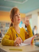 A girl in school, raising her hand