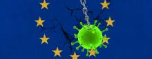 corona virus wrecking ball smashing into wall with EU flag  painted on it