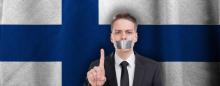 man with tape over his mouth in front of Finnish flag