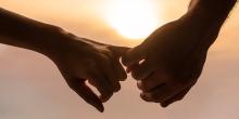 husband and wife's hands with fingers intertwined at sunset