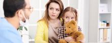 concerned mother with child on lap listening to a doctor talking