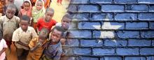 Somalian kids with serious faces next to a brick wall painted like the flag of Somalia