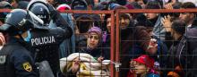 large crowd of migrants attempting to enter Slovenia at a padlocked gate