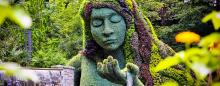 a floral sculpure of a woman with water flowing out of the palm of her hand